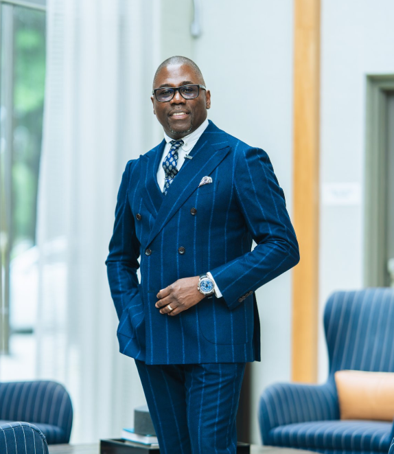 Jerry Pani wearing glasses and a blue suit in an indoor lounge