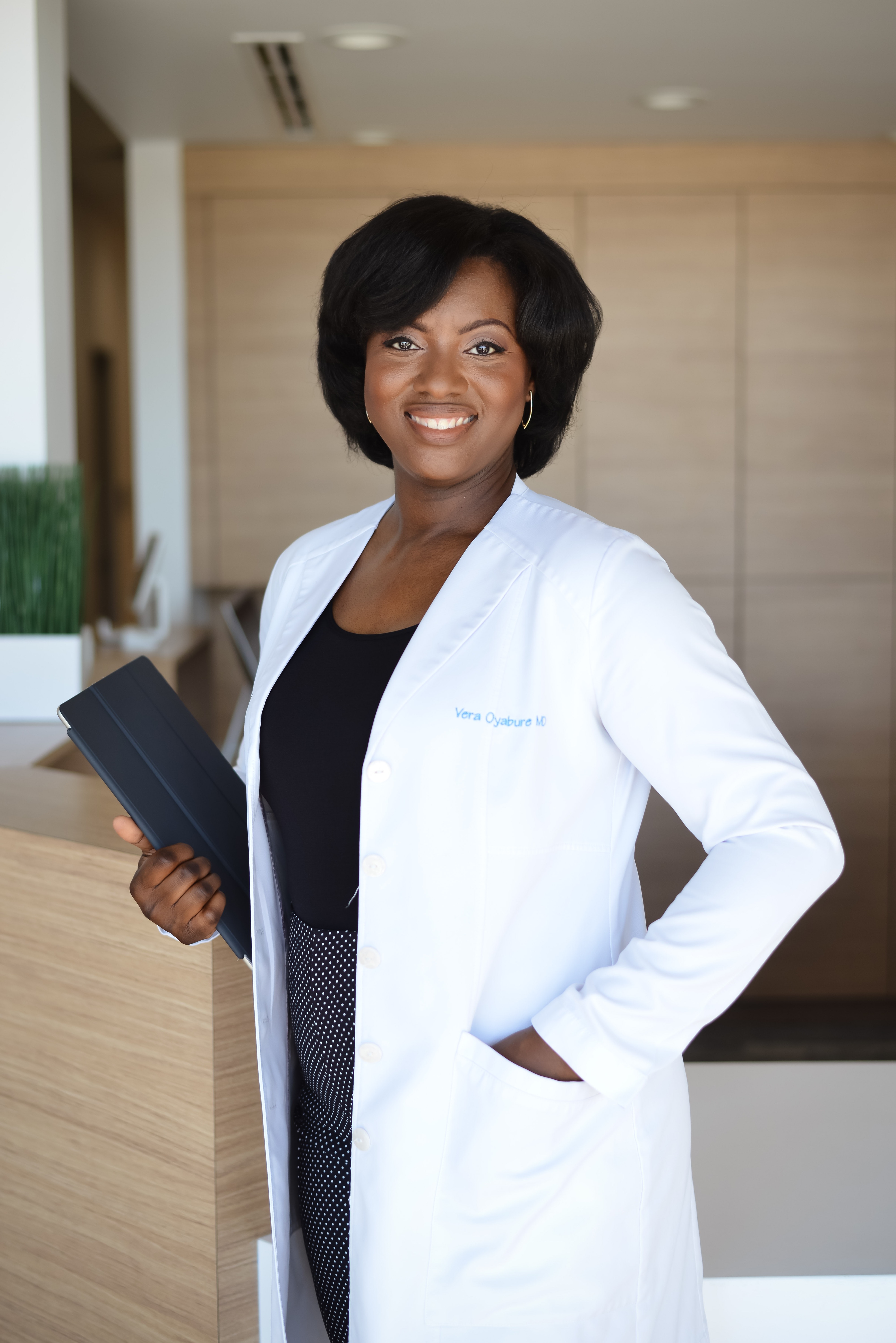Dr. Vera smiling in a white medical coat indoors